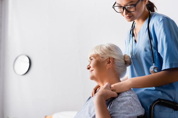 stock-photo-smiling-senior-woman-holding-hand-young-asian-nurse-while-looking